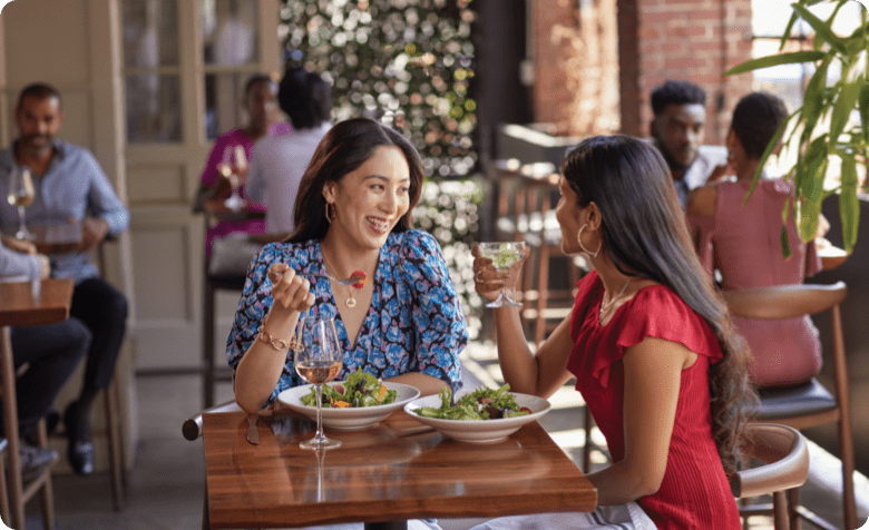 two women eating salad at a restaurant